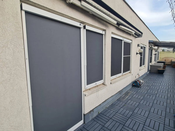 Vertikalmarkise außen an mehreren Fenstern und einer Terrassentür schützt vor Sonne und Hitze an der Hausfassade.